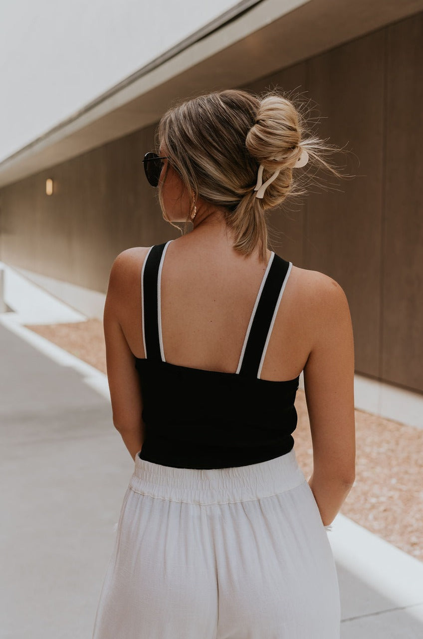 back view of female model wearing the Jane Criss-Cross Halter Tank which features Lightweight Ribbed Fabric, Cropped Tank and Halter Neckline. the tank is available in black and white