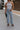 front view of female model wearing the Charli Cropped Wide Leg Pants which features Denim-Like Fabric, Wide Pant Legs, Raw Hem, Monochrome Front Button with Zipper Closure, Two Front Pockets, Two Back Pockets and Belt Loops. the pants are available in blue and pink.