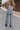 back view of female model wearing the Charli Cropped Wide Leg Pants which features Denim-Like Fabric, Wide Pant Legs, Raw Hem, Monochrome Front Button with Zipper Closure, Two Front Pockets, Two Back Pockets and Belt Loops. the pants are available in blue and pink.