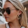 Side view of female model wearing the Davina Gold Teardrop Earrings that have post backs and 3 gold metal teardrop pendants that are connected.