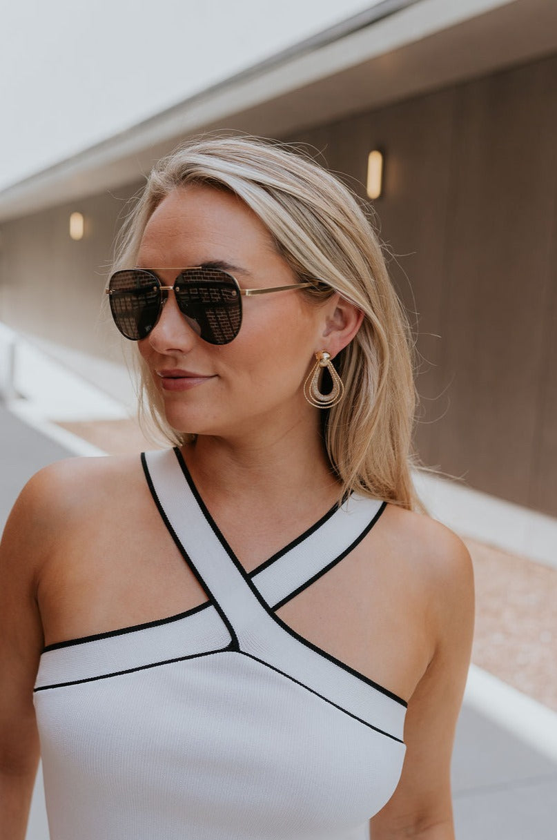 Side view of female model wearing the Davina Gold Teardrop Earrings that have post backs and 3 gold metal teardrop pendants that are connected.