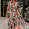 Full body view of female model wearing the Alora Multi Palm Floral Midi Dress which features Multi Color Floral Palm Print, Tan Lining, Tiered Body, Midi Length, Quarter Button-Up, Collared Neckline and Short Puff Sleeves