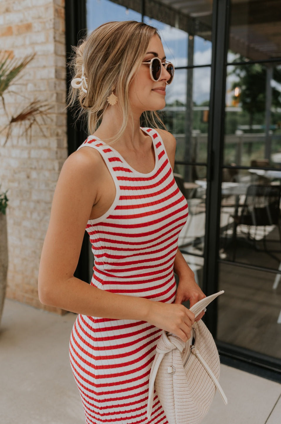 Upper body side view of female model wearing the Delilah Red & White Striped Midi DressDelilah Red & White Striped Midi Dress that has horizontal red and white stripes, a round neck, sleeveless, and midi hem.