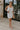 Full body view of female model wearing the Diana White Bow Straps Mini Dress which features White Cotton Fabric, White Lining, Mini Length, Square Neckline, Bow Details, Thick Straps and Monochrome Back Zipper with Hook Closure