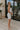 Full body side view of female model wearing the Diana White Bow Straps Mini Dress which features White Cotton Fabric, White Lining, Mini Length, Square Neckline, Bow Details, Thick Straps and Monochrome Back Zipper with Hook Closure