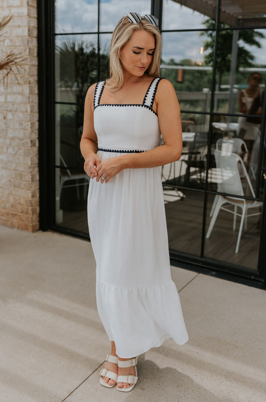 Full body view of female model wearing the Saylor White & Navy Scallop Midi Dress which features White Lightweight Fabric, Navy Scallop Details, Peplum Hem, Midi Length, White Lining, Square Neckline and Monochrome Back Zipper with Hook Closure