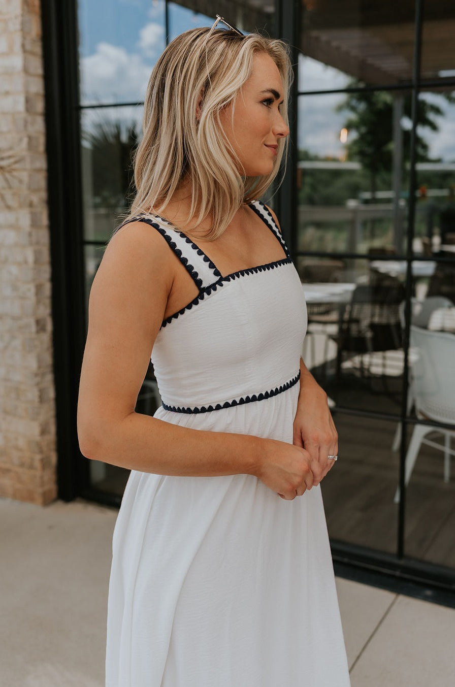 side view of female model wearing the Saylor White & Navy Scallop Midi Dress which features White Lightweight Fabric, Navy Scallop Details, Peplum Hem, Midi Length, White Lining, Square Neckline and Monochrome Back Zipper with Hook Closure