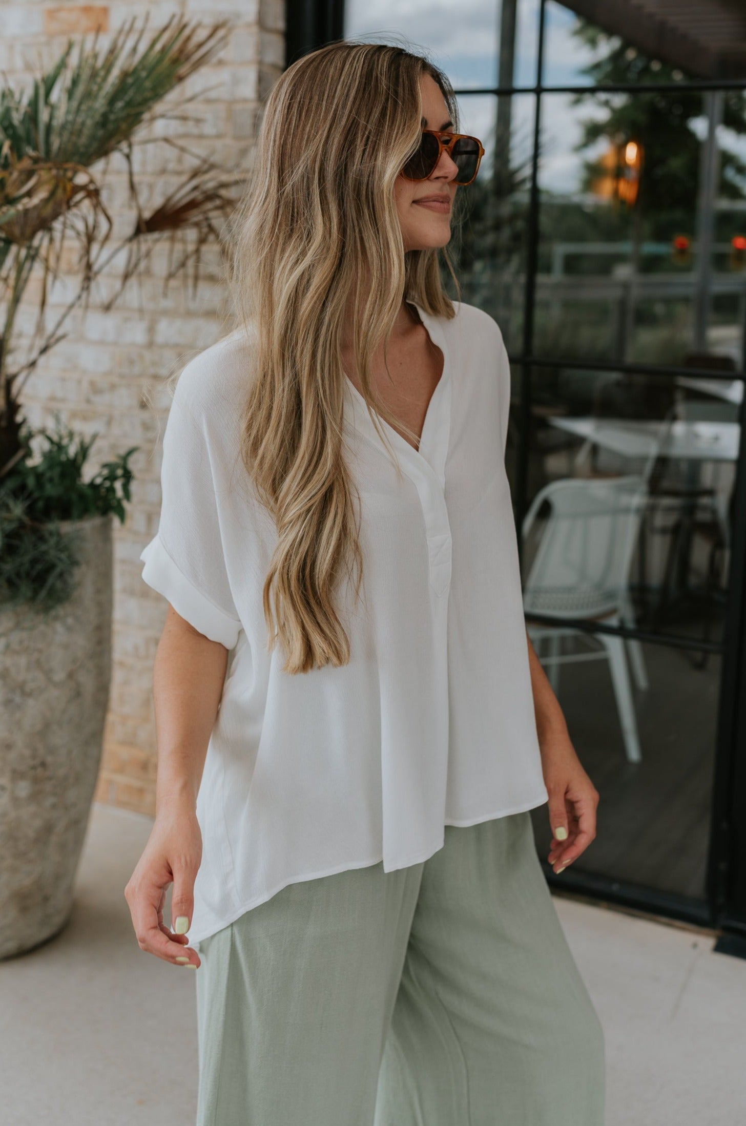 side view of female model wearing the Evie White Short Sleeve Button-Up Top which features Evie White Short Sleeve Button-Up Top