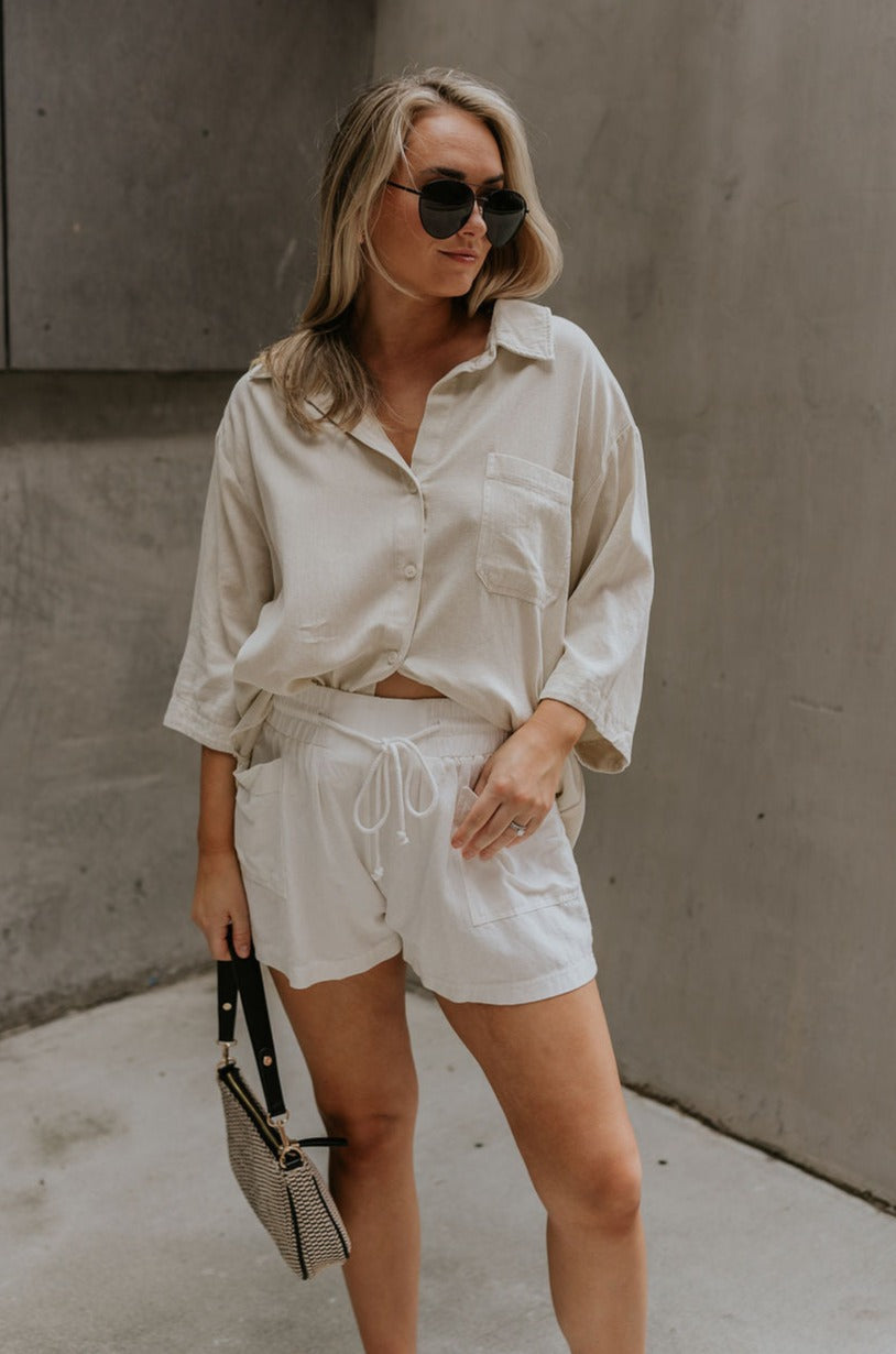 Full body view of female model wearing the Andrea Ecru Button-Up Top which features Ecru Cotton Fabric, Monochrome Button-Up Top, Collared Neckline, Front Left Chest Pocket and Short Sleeves