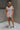 Full body front view of model wearing the Hadley Light Pink Short Sleeve Top that has light pink knit fabric, a chest pocket, v neck, and short sleeves.