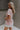 Upper body side view of model wearing the Hadley Light Pink Short Sleeve Top that has light pink knit fabric, a chest pocket, v neck, and short sleeves.