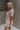 Upper body side view of model wearing the Hadley Light Pink Short Sleeve Top that has light pink knit fabric, a chest pocket, v neck, and short sleeves.