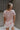 Upper body back view of model wearing the Hadley Light Pink Short Sleeve Top that has light pink knit fabric, a chest pocket, v neck, and short sleeves.