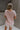 Upper body back view of model wearing the Hadley Light Pink Short Sleeve Top that has light pink knit fabric, a chest pocket, v neck, and short sleeves.
