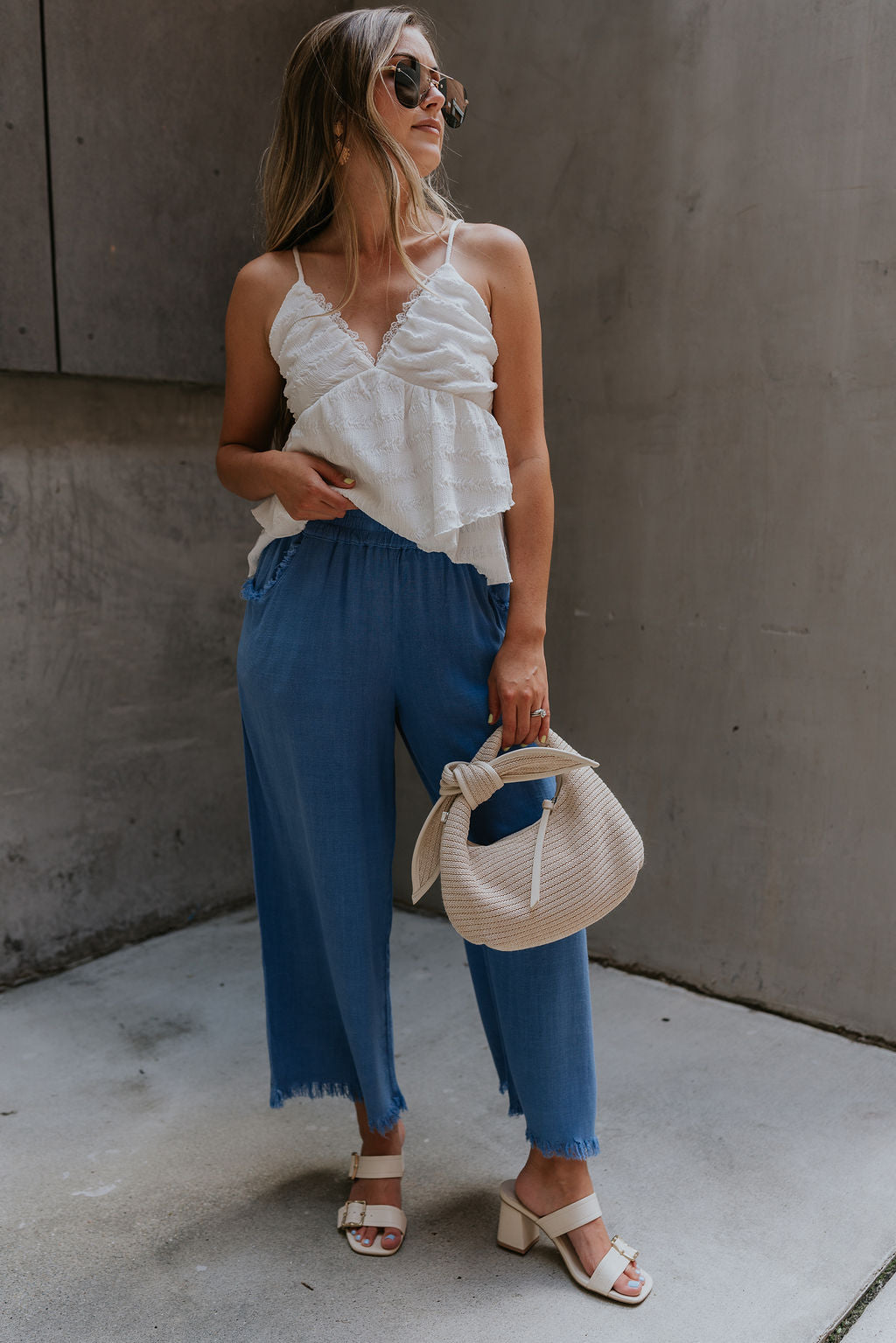 Full body view of female model wearing the Leona Linen Fray Cropped Pants which features Lightweight Fabric, Wide Cropped Leg, Fray Hem Details, Two Front Pockets and Elastic Waistband. the pants are available in blue, green and white.