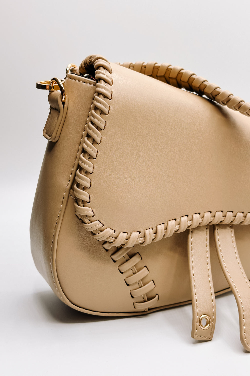 Front view of the Sloane Sand Leather Braided Strap Purse which features tan leather fabric, braided details, gold clasp closure, braided strap, tan lining and curvy hem shape