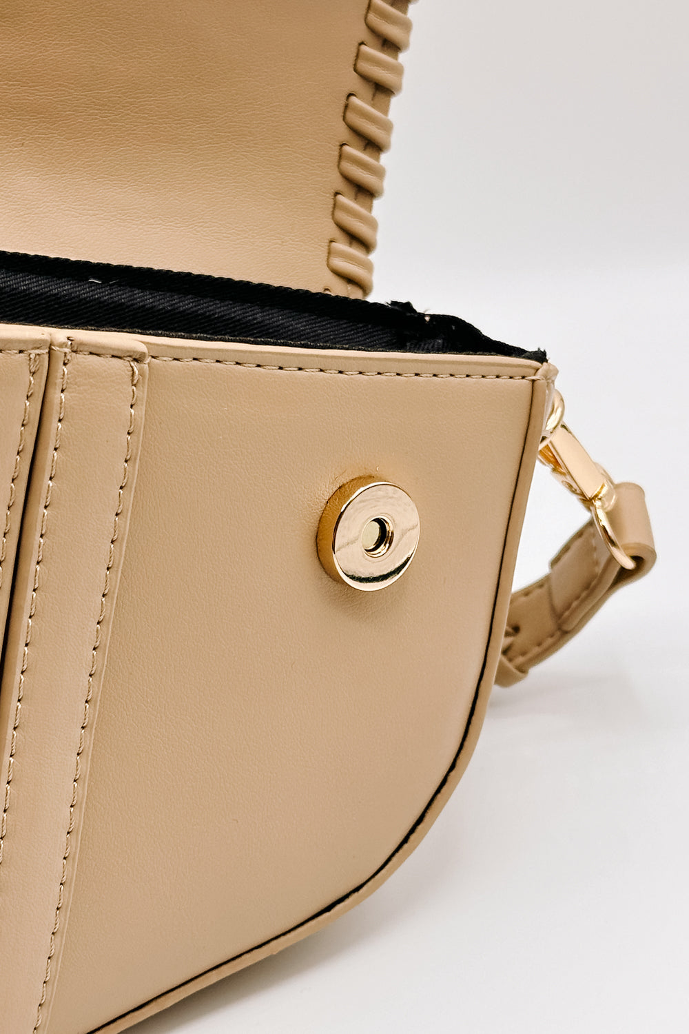 close up  view of the Sloane Sand Leather Braided Strap Purse which features tan leather fabric, braided details, gold clasp closure, braided strap, tan lining and curvy hem shape