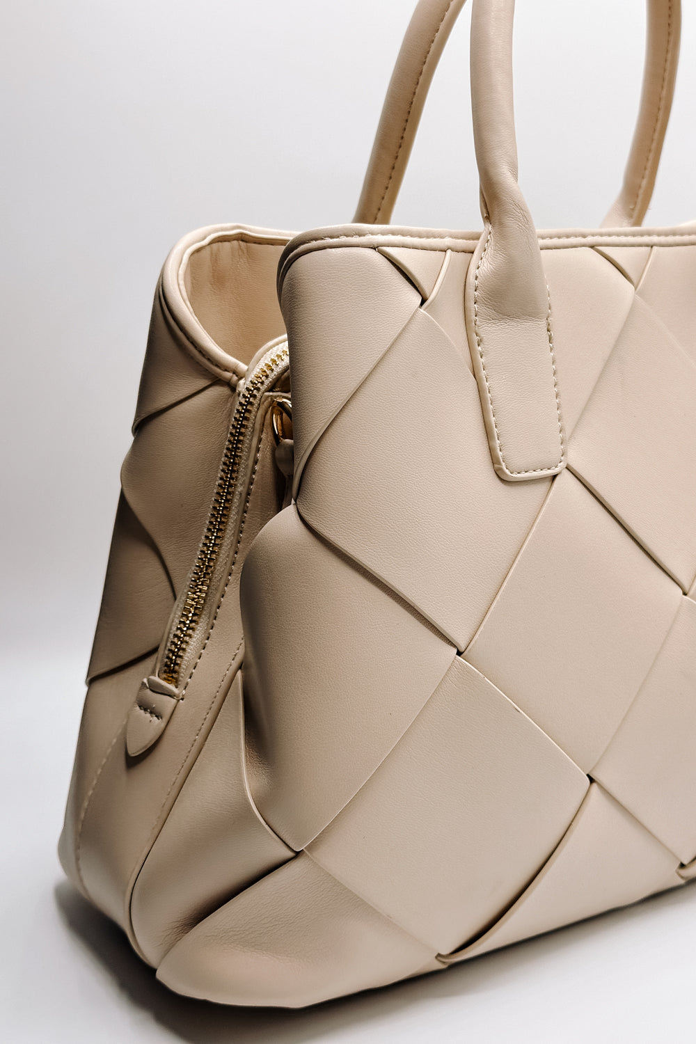 Close up side view of the Phoebe Cream Woven Leather Purse which features cream leather fabric, woven pattern details, gold hardware, monochrome straps, zipper closure and gold clasp closure