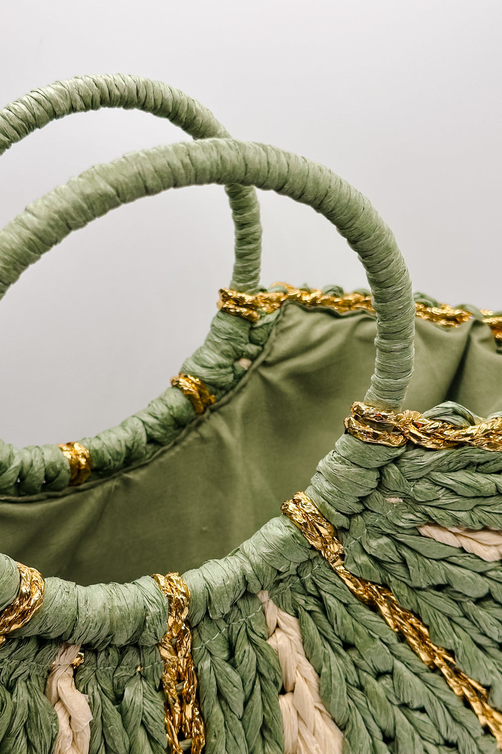 close up view of the Aurora Olive & Natural Woven Tote which features sage and natural woven braided fabric, gold thread details, round handles and sag lining