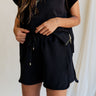 front view of female model wearing the Camilla Black Drawstring Shorts which features Black Ribbed Fabric, Side Pockets and Elastic Waistband with Drawstring Ties