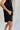 side view of female model wearing the Camilla Black Drawstring Shorts which features Black Ribbed Fabric, Side Pockets and Elastic Waistband with Drawstring Ties