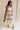 Full body view of female model wearing the Clara Ecru & Black Wavy Trim Midi Dress which features Cream Lightweight Fabric, Cream Lining, Midi Length, Pockets on each side, Black Wavy Trim Details, Square Neckline, Straps and Smocked Back