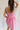 back view of female model wearing the Caroline Pink & White Floral Mini Dress which features Pink Lightweight Fabric, White Flower Pattern, Pink Lining, Ruffle Sweetheart Neckline, White Tie Straps and Monochrome Back Zipper with Hook Closure