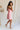 Full body side view of female model wearing the Eliza Pink Square Neckline Mini Dress which features Lightweight Pink Fabric, Pink Lining, Mini Length, Square Neckline, Sleeveless and Monochrome Back Zipper with Hook Closure