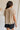 back view of female model wearing the Celine Taupe Pleated Short Sleeve Top which features Taupe Pleated Fabric, Taupe Lining, Round Neckline, Short Sleeves, Ruffle Hem and Back Key Hole with Button Closure