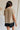 back view of female model wearing the Celine Taupe Pleated Short Sleeve Top which features Taupe Pleated Fabric, Taupe Lining, Round Neckline, Short Sleeves, Ruffle Hem and Back Key Hole with Button Closure
