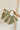 Model's hand is holding the Aurora Olive & Natural Woven Tote which features sage and natural woven braided fabric, gold thread details, round handles and sag lining