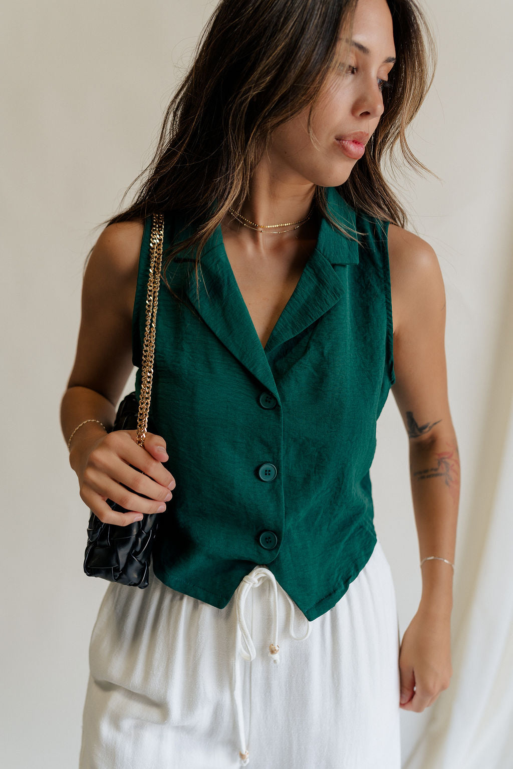 front view of female model wearing the Reign Hunter Green Buttoned Vest which features Hunter Green Lightweight Fabric, Monochrome Button Up, Collared Neckline and Sleeveless