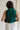 back view of female model wearing the Reign Hunter Green Buttoned Vest which features Hunter Green Lightweight Fabric, Monochrome Button Up, Collared Neckline and Sleeveless