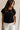 front view of female model wearing the Colette Black Cut-Out Short Sleeve Top which features Black Lightweight Knit Fabric, Cutout Details, Round Neckline and Short Sleeves