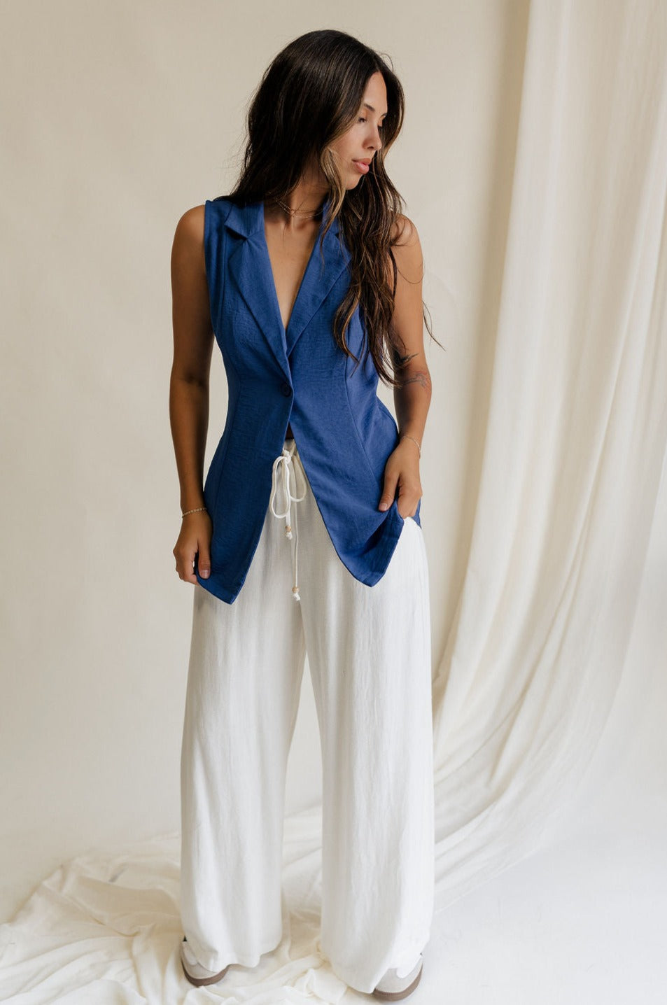 Full body view of female model wearing the Faye Blue Buttoned Vest which features Blue Lightweight Fabric, Monochrome Button Closure, Collared Neckline and Sleeveless