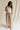 Full body front view of female model wearing the Winnie Brown & Cream Striped Pants, that feature vertical brown and cream stripes, wide legs, and a drawstring waist.