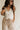Upper body front view of female model wearing the Winnie Brown & Cream Striped Pants, that feature vertical brown and cream stripes, wide legs, and a drawstring waist.