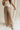 Lower body front view of female model wearing the Winnie Brown & Cream Striped Pants, that feature vertical brown and cream stripes, wide legs, and a drawstring waist.