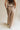 Back view of female model wearing the Winnie Brown & Cream Striped Pants, that feature vertical brown and cream stripes, wide legs, and a drawstring waist.