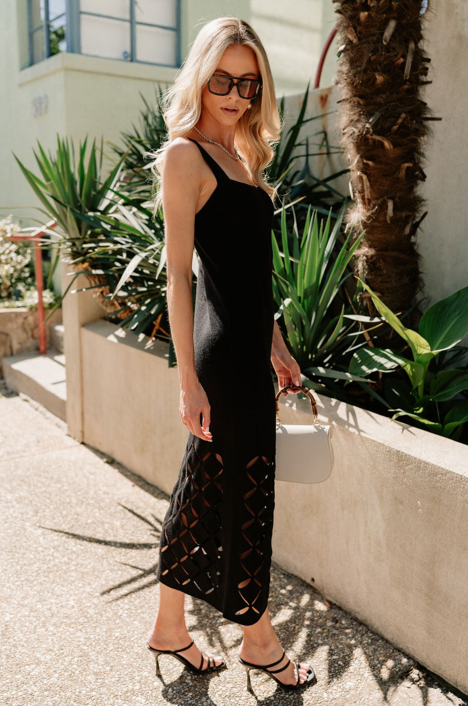 Full body side view of female model wearing the Mila Black Knit Cut-Out Trim Midi Dress which features Black Knit Fabric, Square Neckline, Straps and Cutout Details