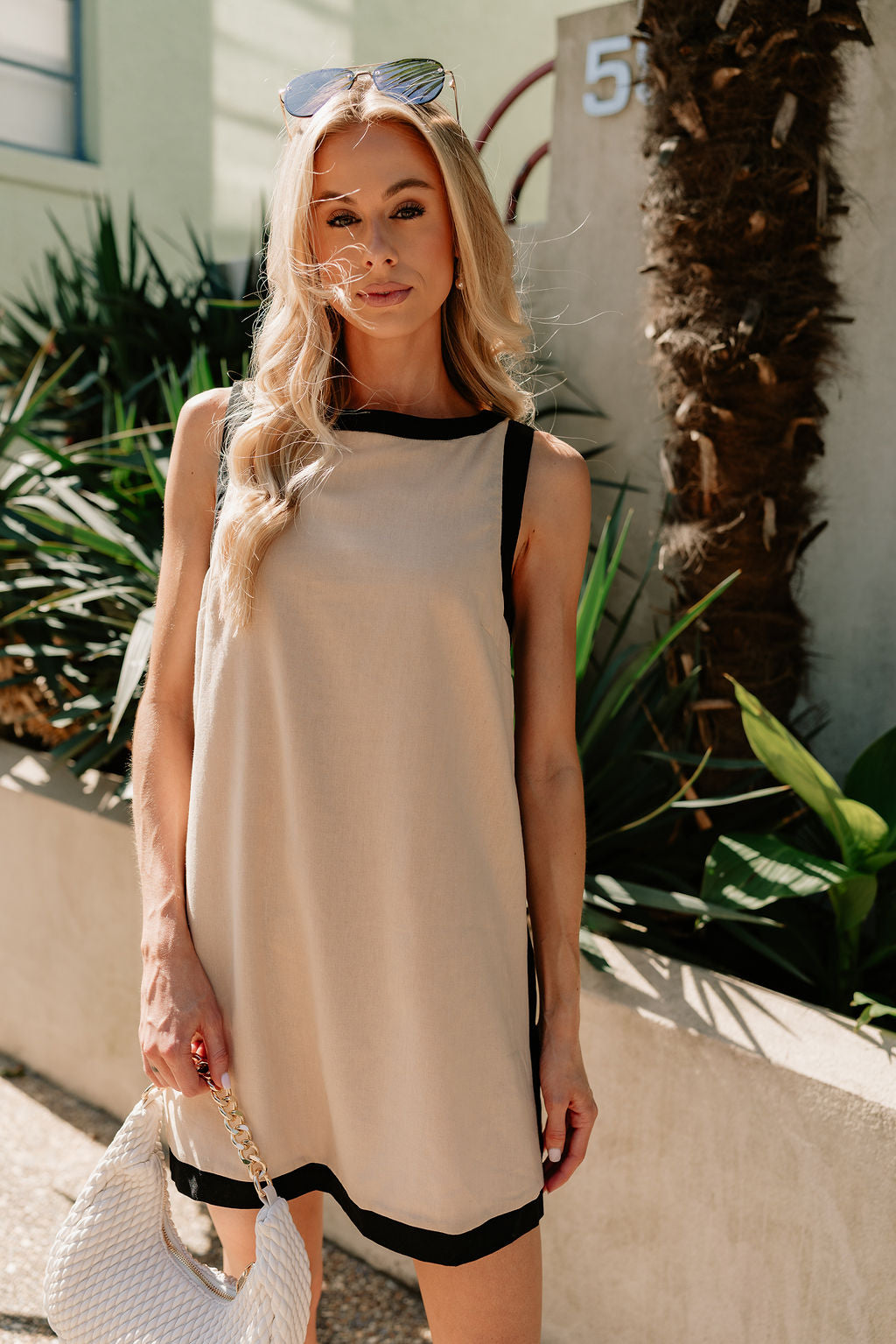 Front view of female model wearing the Camila Oatmeal & Black Sleeveless Mini Dress which features Tan Linen Fabric, Black Trim Details,Tan Lining, Mini Length, Round Neckline, Sleeveless and Monochrome Back Zipper with Hook Closure