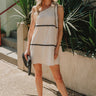 full body view of female model wearing the Aria Oatmeal & Black Wavy One-Shoulder Mini Dress which features Cream Linen Lightweight Fabric, Cream Lining, Mini Length, Black Wavy Trim Details and One Shoulder Strap with Bow Tie