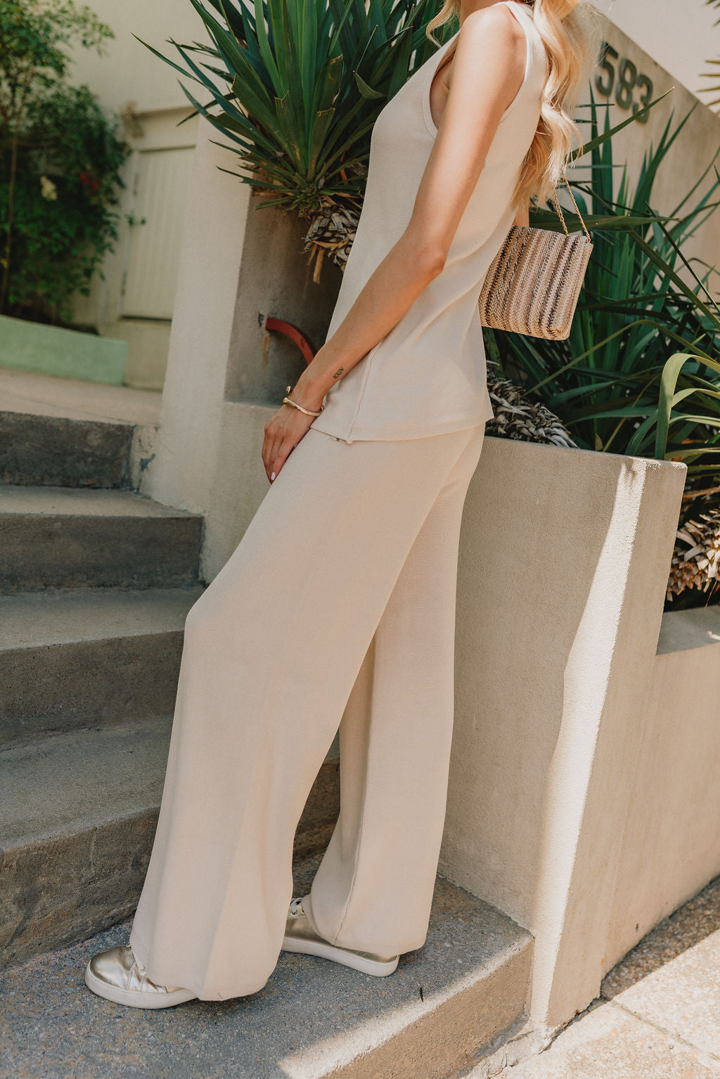 side view of female model wearing the Lillian Ecru Ribbed Pants which features Ecru Lightweight Fabric, Wide Leg, Slight Cropped Pant Legs and Elastic Waistband