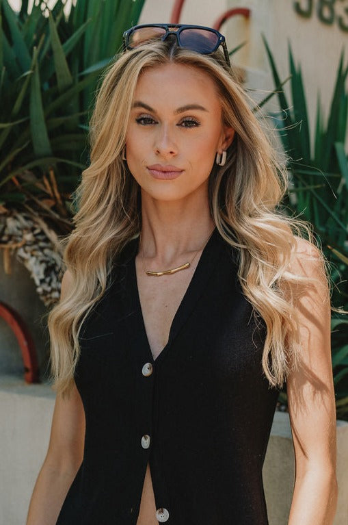 front view of female model wearing the Julie Gold Bar Chain Link Necklace which features gold wave bar medallion with an adjustable clasp closure