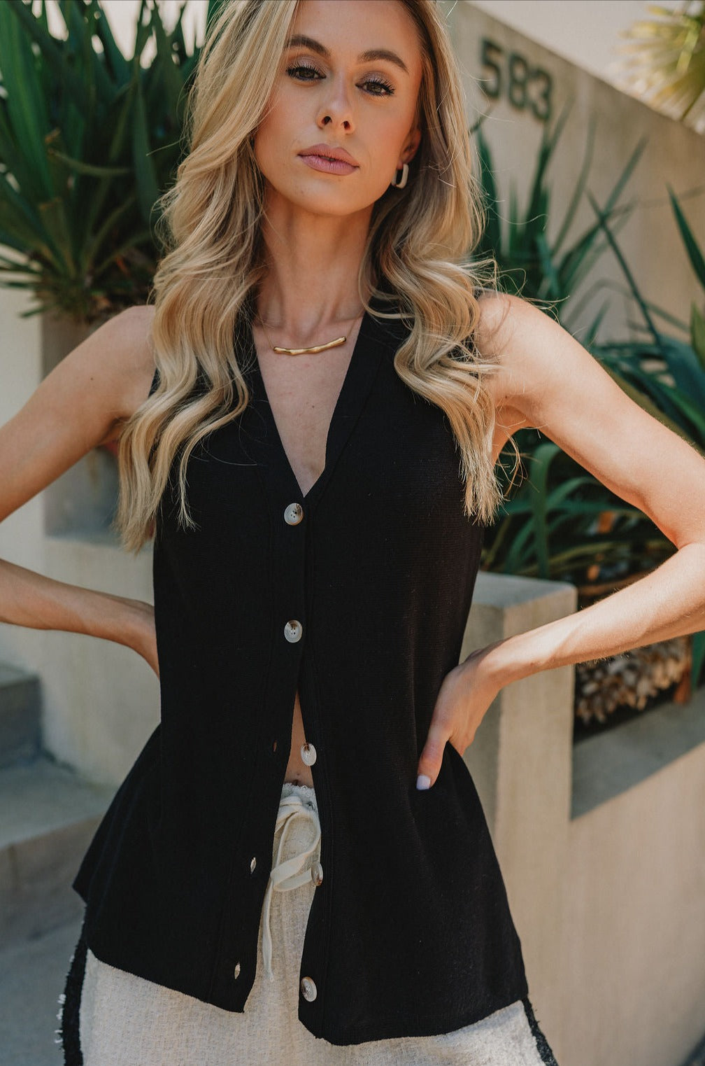 Front close up of  Lydia Button Up Tank in Black that is sleeveless with tortoise buttons and a deep V neckline.