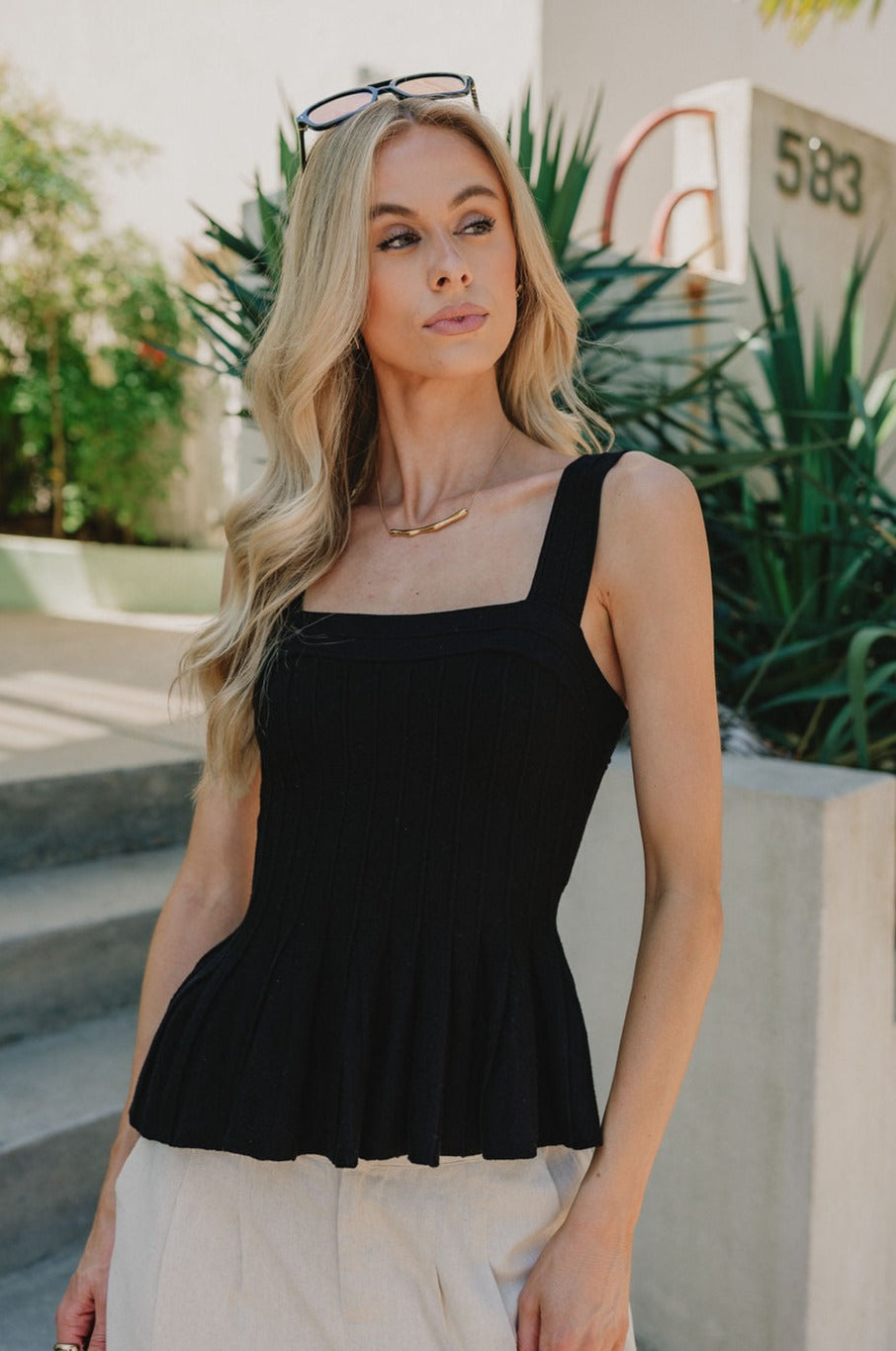 Front view of female model wearing the Juliana Ribbed Flare Tank which features Ribbed Fabric, Flare Hem Detail, Square Neckline, Thick Straps and Sleeveless. the tank is available in black and white.