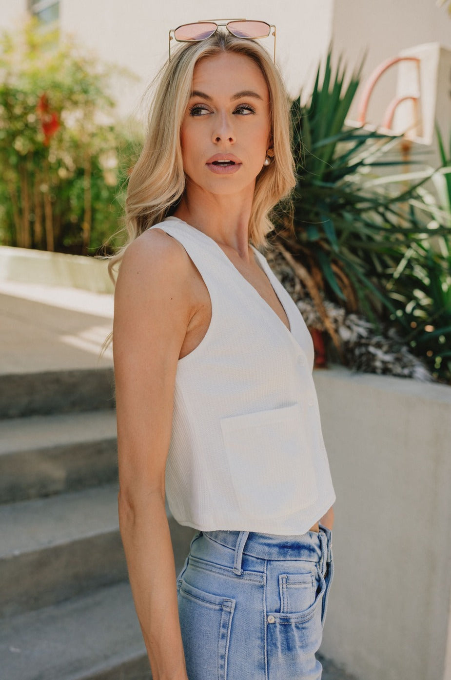 side view of female model wearing the Londyn Off White Button-Up Vest which features White Textured Fabric, Monochrome Button Up, Two Front Pockets, V-Neckline and Sleeveless