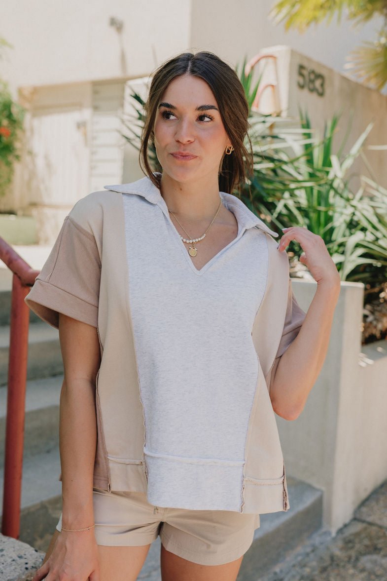 Close up front view of Malia Multi-Color Short Sleeve Top that is taupe, mocha, and grey, with a V and collared neckline, beautiful detailing of a heart on the back.