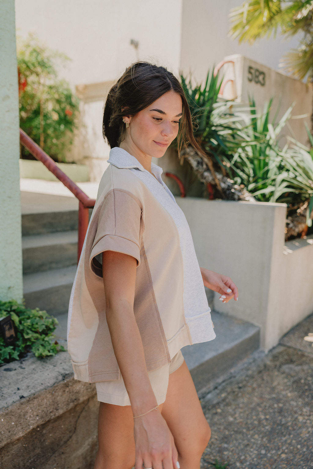 Side view of Malia Multi-Color Short Sleeve Top that is taupe, mocha, and grey, with a V and collared neckline, beautiful detailing of a heart on the back.