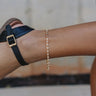 side view of female model wearing the Samara Gold & Pearl Adjustable Chain Anklet which features adjustable gold and pearl chain anklet